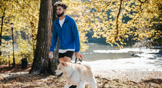 Man walking with dog outdoors.