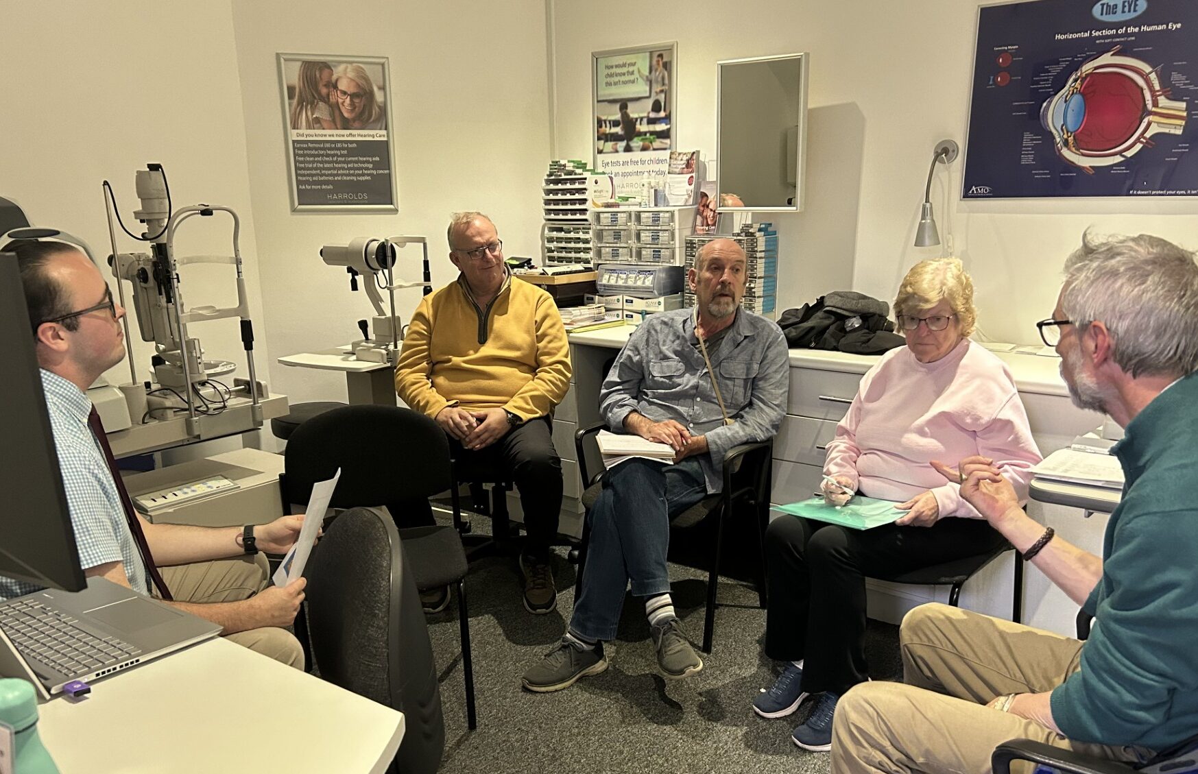 A photo showing a group of five people sitting in an audiologist's clinic having a conversation