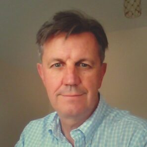 A portrait of Robin Greenwood, Interim Chief Executive of Tinnitus UK. Robin is looking directly at the camera and wearing a pale blue shirt.